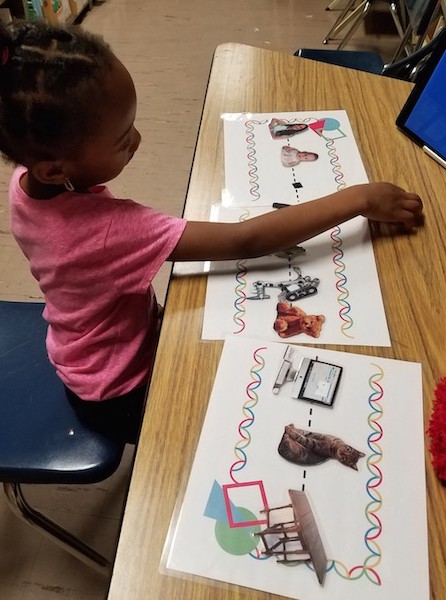 a girl sits at a table with paper and pictures of different robots and things