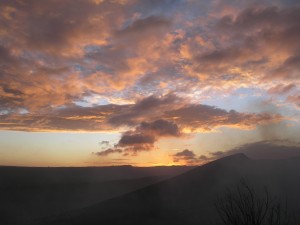 pink clouds spread across a pastel sky, smoke rising below from masaya volcano, lit from the last sunlight of the day