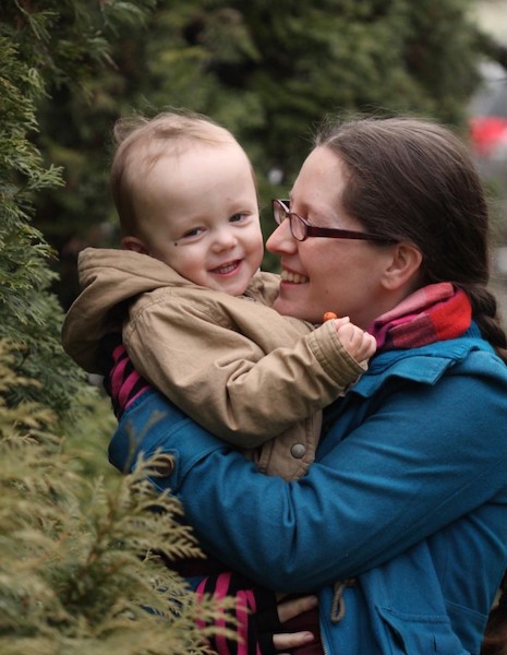 me hugging little Elian in front of evergreens